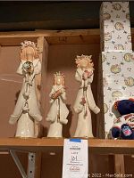 Set of three porcelain faceless figurines with 911 hair design and telephone elements on shelf.