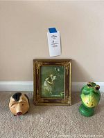 Full view of all items arranged on floor: piggy bank, frog figurine, framed photo/artwork