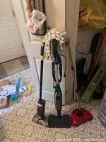 Shark Genius wet mop, Shark Vacmop wet mop, red Easy Edge broom, HandiMop in packaging leaning against door