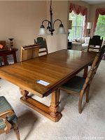 Full view of the solid wood dining table in a dining room setting, showing the tabletop and surrounding chairs.