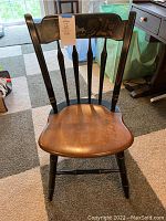 Full view of the Ethan Allen wooden side chair with a smooth wooden seat and black painted thumb backrest with vertical spindles.