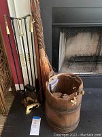Wooden bucket, broom, and metal fireplace tool stand next to a fireplace