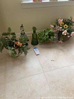 Overview of three flower and plant baskets and two glass decorative items on the floor near a wall.