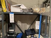 Wide shot of the shelving unit containing books including home repair, medical manual, gem collecting materials, plastic coffee mugs, and part of the condensate pump.