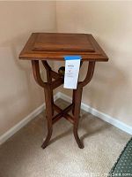 Front angled view of solid wooden end table highlighting the square top, curved legs, and part of the pedestal base with crossed stretcher and decorative ball.