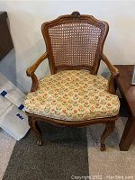 Wooden side chair with caned back and floral cushioned seat, carved wooden frame with claw feet.