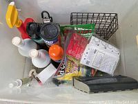 Plastic tub with various pest control and bird feeding items including suet feeders, sprays, and traps.