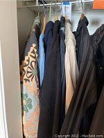 Wide view of seven women's coats hanging, including a floral patterned coat, denim coat, and black coats.