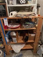 Wood shelving unit in basement storage area, showing shelf levels and some items stored but not included in sale.