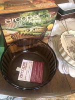 Arcopal Gourmet Fumé soufflé bowl with original box and several ceramic dishes including quiche dishes, Pyrex mixing bowl, and metal cooking utensils