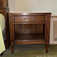 Full view of first bedside table showing top drawer with metal hardware and bottom open shelf.