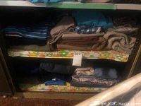 Folded assorted fabrics on shelves including brown and blue colors and some striped patterns.