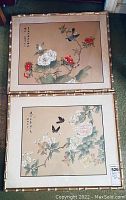 Two framed Asian floral prints with bamboo style frames laid on floor