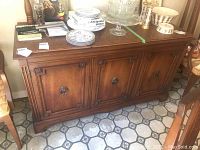 Front view showing three doors, the paneled decorative design, and items on top (not included).