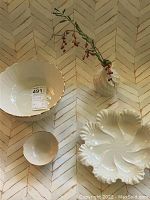 Four Lenox China pieces on table: large scalloped bowl with green Lenox logo, small gold-trimmed bowl, serving bowl with gold trim, and geometric bud vase with gold trim and red berries inside.