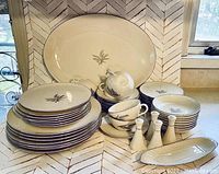 Full set of Lenox fine china including plates, cups, saucers, butter dish, salt and pepper shakers are shown arranged on a counter.