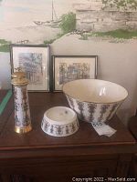 Wide view showing Lenox bowls, salt and pepper shakers with two framed prints behind on a wooden dresser