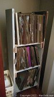 Bookshelf filled with vertically stored vinyl records albums in worn and aged sleeves and jackets