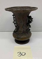 Solid bronze antique Japanese vase front view showing flared mouth, textured patterns, and mythical animal attached figures.