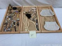 Full lot overview showing jewelry, figurines, and bags arranged on wooden trays