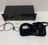 Bose headphones with case and cord alongside AudioSource EQ-One unit on white surface.