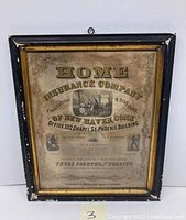 Front view of entire framed Home Insurance Company print showing intact frame with minor damage and wear, print visible with some water stains.