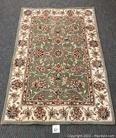 Full view of the rectangular oriental traditional rug featuring floral patterns in green, beige, and red tones.