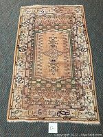 Full view of hand-knotted Turkish scatter rug with beige central medallion, green and cream borders, pattern details visible