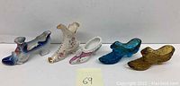 Five shoe ornaments arranged in a row showing mix of porcelain and glass pieces with floral and colored decoration.