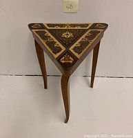 Front angled view of the small triangular table with three legs and marquetry inlay tabletop.