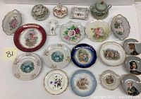 Overview of entire porcelain trinkets collection showing multiple plates, dishes, and portrait plaques with floral and scenic designs.