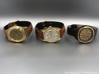 Full view of three vintage wristwatches with leather straps, arranged side by side, showing overall design and style.