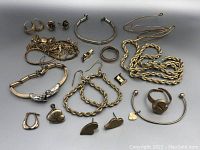 Photo showing the full assortment of gold filled jewelry laid out on a gray background, including bracelets, rings, chains, and earrings.