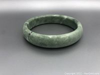 Side profile of green jade bangle on grey background