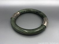 Photo of jade bracelet closed showing the circular shape and green polished surface with silver end caps.
