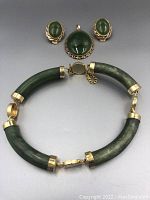 Full set of jade jewelry with bracelet, earrings and pendant displayed against a neutral background.