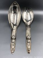 Photo shows front side of the large salad spoon and fork with tribal figure sculptures on handles.