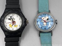 Both Mickey Mouse and Snoopy watches side by side showing full watch faces and straps.