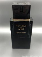 Front view of a black rectangular Van Cleef & Arpels Eau de Toilette perfume bottle with a gold-tone band near the top and a black cap with silver decorative elements.