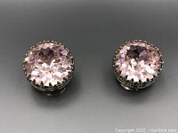Front view of the pair of round pink cut crystal earrings, showing the sparkle and detailed metal setting.