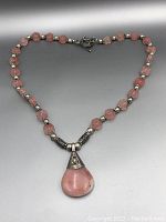 Full view of pink gemstone necklace laid out with toggle clasp visible and teardrop pendant centered.