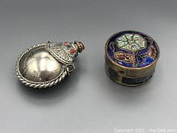 Top angled view of the silver-toned snuff bottle and cloisonné pill box showing the snuff bottle with red and green stone decorations and the round pill box with a blue and green floral cloisonné lid.