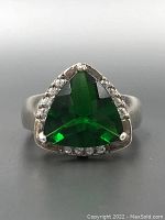 Front view of the sterling silver ring displaying a triangular green gemstone surrounded by small clear stones.