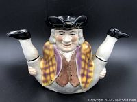 Front view showing detailed facial expression, hat, checked jacket, and raised legs.