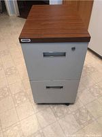 Front view of the 2 drawer metal file cabinet with wood grain laminate top showing drawer handles and lock