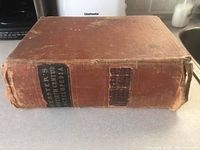 Front view of the spine of the encyclopedia showing the title and wear on the binding.