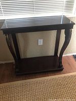 Front view of the dark wood console table showing carved curved legs and lower shelf beneath the top.