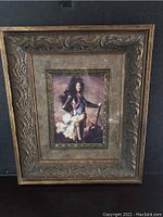 Full view of ornate antiqued gold finish frame with inner print of Louis XIV.