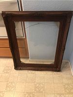 Full view of one large rectangular decorative frame with brown color wash and intact glass showing the design and overall condition.