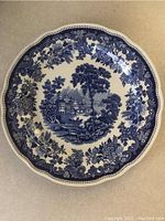 Top view of the blue and white decorative plate showing the scenic countryside estate surrounded by floral patterns.